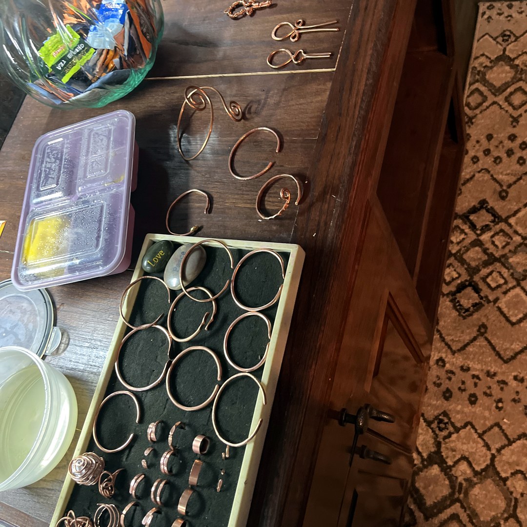 Studio overview — earrings on rack, bangles, rings on foam tray
